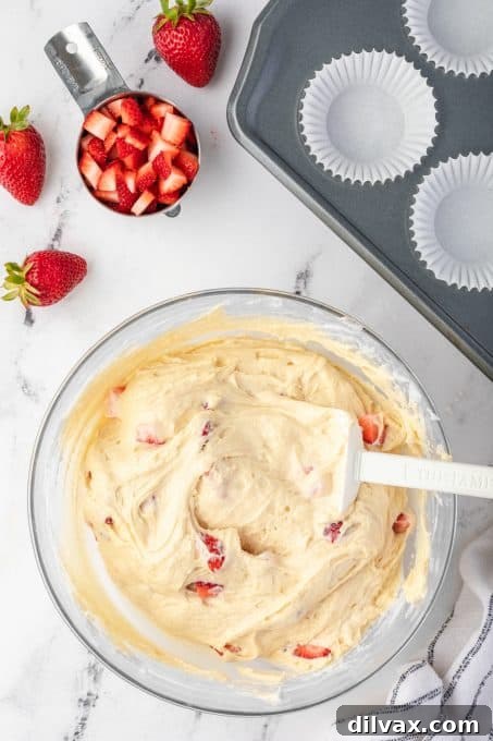 Muffin batter with diced strawberries visible, ready to be baked.