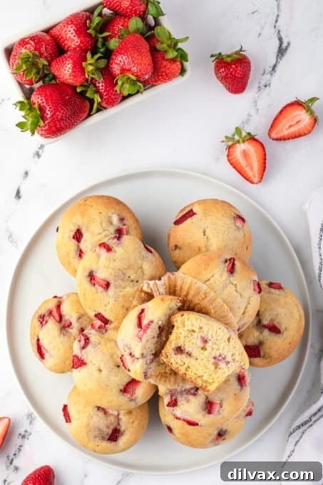 A beautifully arranged plate of freshly baked strawberry muffins with whole strawberries.