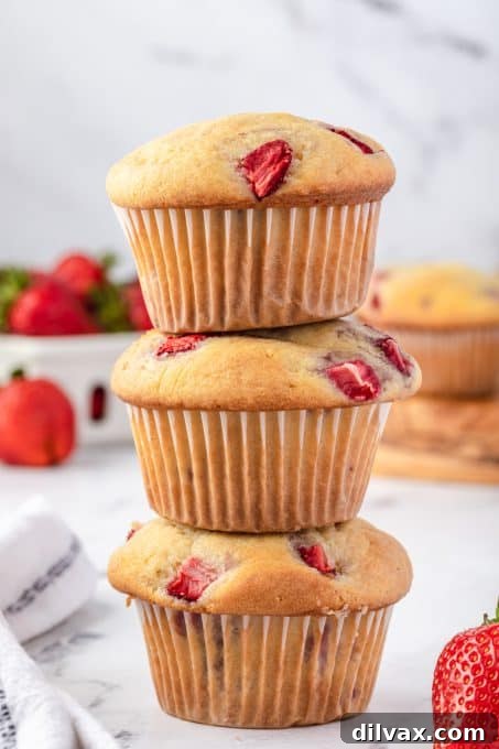 A stack of golden-brown strawberry muffins on a cooling rack.