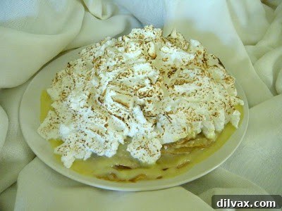 A perfectly sliced piece of lemon meringue cardamom crepe cake on a white plate, showing distinct layers.