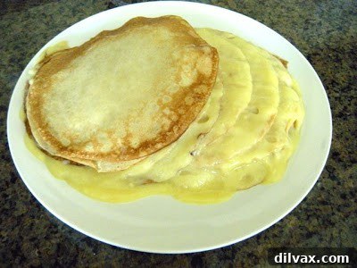 An unstable, partially collapsed lemon meringue crepe cake on a serving plate, showing assembly difficulties.