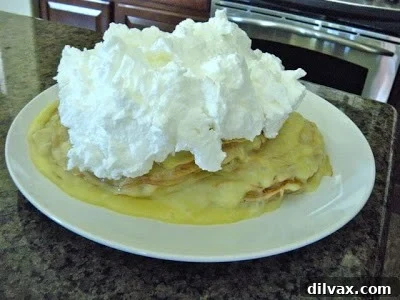 Fluffy meringue topping elegantly spread on a layered crepe cake, ready for torching.
