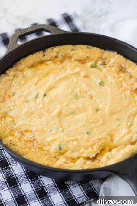 Cast iron skillet cornbread batter ready for the oven, topped with jalapeño slices.