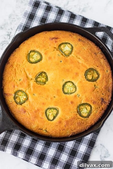 A cast iron skillet filled with golden brown Jalapeño Cheddar Cornbread.
