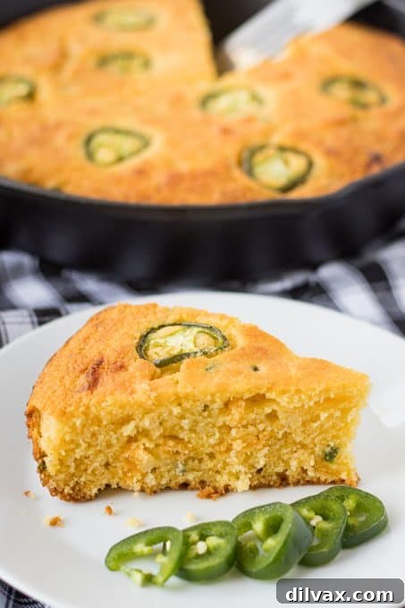 Cheesy cornbread with jalapeños baked in a skillet, showcasing the golden-brown crust.