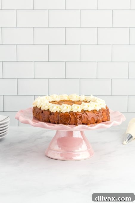 A cinnamon cake with icing on a cake plate.