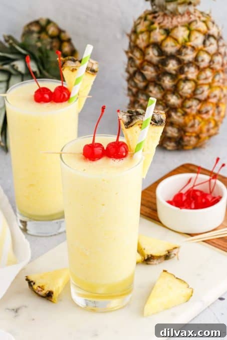 A refreshing Pineapple Coconut Rum Cocktail served in a hurricane glass with a pineapple wedge and cherry garnish.