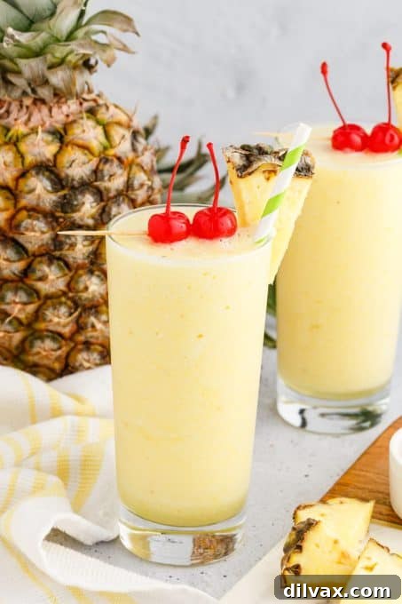 A close-up shot of a Coconut Rum Cocktail featuring pineapple chunks and a cocktail umbrella.