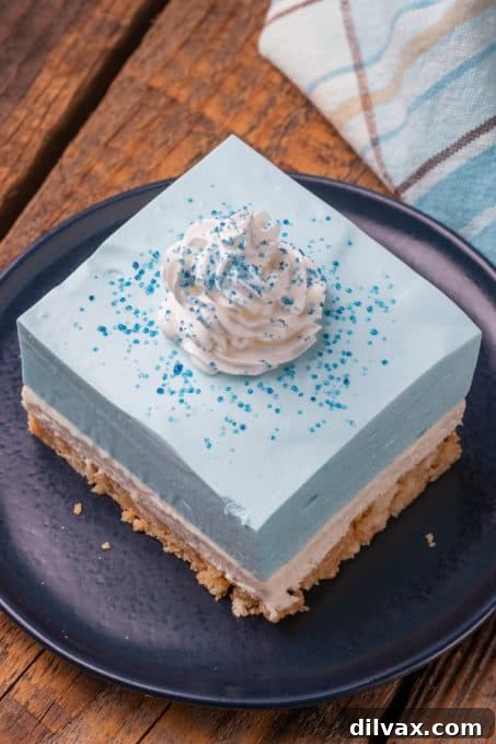 Electric Blue Raspberry Bars 7 The vibrant top layer of a Dream Bar made with blue raspberry Jello, adorned with whipped cream and blue sprinkles.