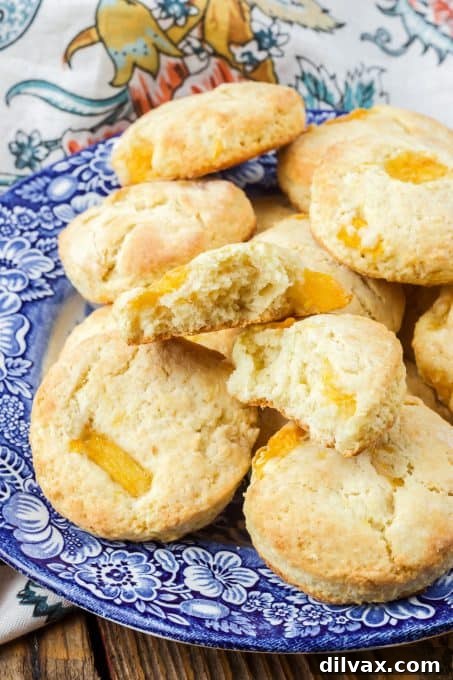 A close-up of a peach scone with a bite taken out, revealing the soft interior and fresh peach chunks.