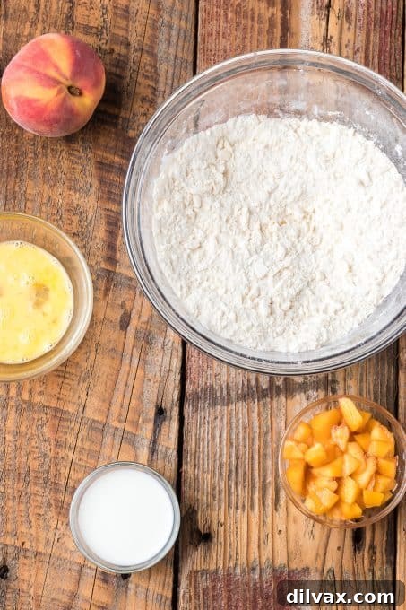 Diced fresh peaches being gently mixed into a scone dough in a large bowl.