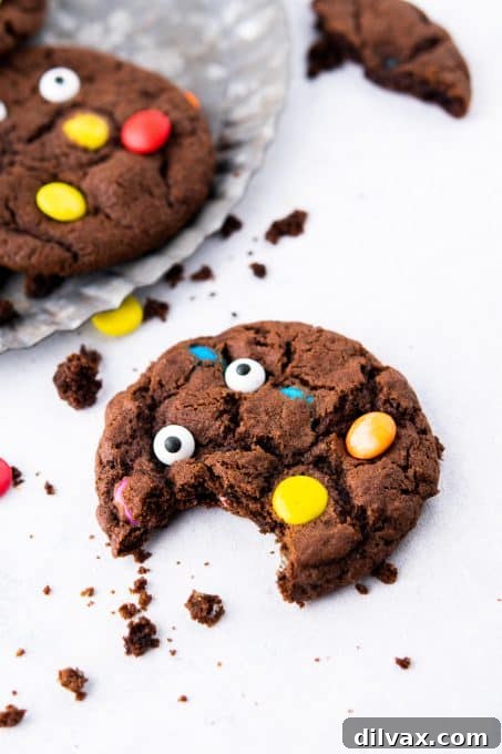A chocolate monster cookie with a bite taken out, showing the M&M's inside.
