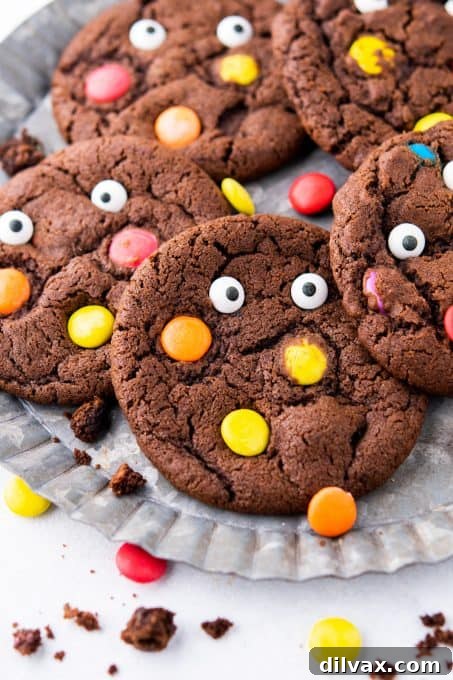 A pile of chocolate M&M cookies with candy eyes, ready for a Halloween party.