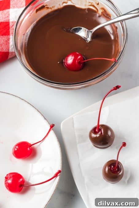 Decadent Three Ingredient Chocolate Covered Cherries 5 A maraschino cherry being dipped into a bowl of melted chocolate.