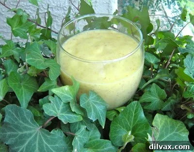 Close-up image of a creamy Pineapple Mango Smoothie in a clear glass.