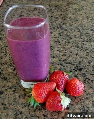 A glass of vibrant purple Blackberry Strawberry Smoothie, garnished with fresh berries.