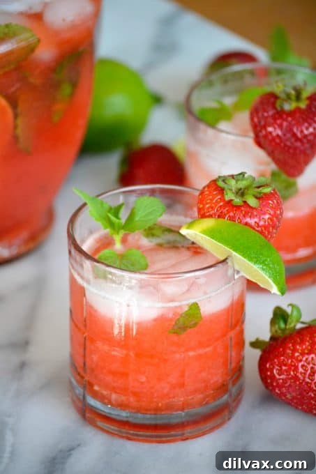 Two glasses of refreshing Strawberry Mojitos, garnished with fresh mint leaves and strawberry slices, perfect for a summer evening.