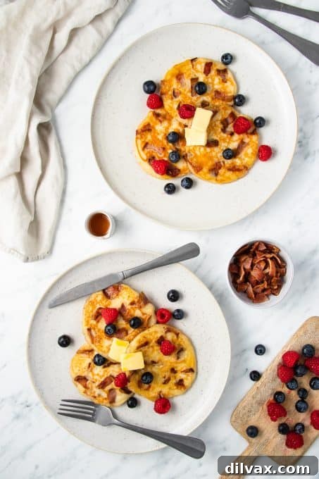 A close-up view of fluffy buttermilk pancakes with visible pieces of crispy bacon inside, ready for a delicious breakfast.