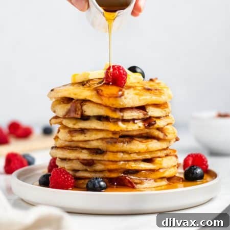 A stack of golden Bacon Pancakes with butter and syrup.