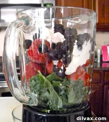 Unveiling the Secret Recipe Club's Berry Blast Green Smoothie 4 A pitcher of freshly blended Berry Blast Green Smoothie being poured into a tall, clear glass, showcasing its smooth texture.