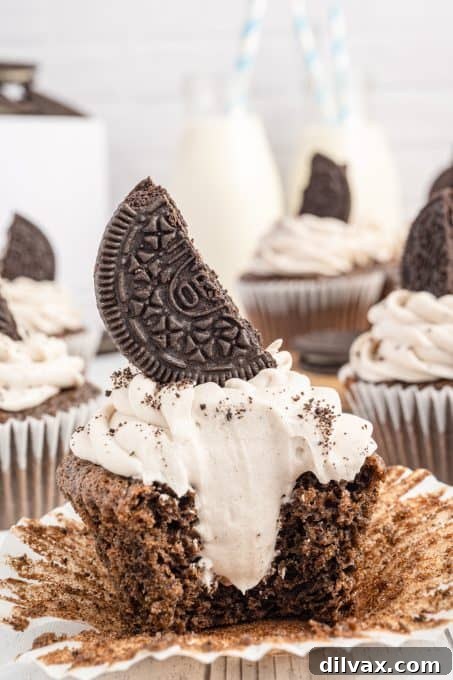 An Oreo Cupcake with Oreo Cream Cheese frosting on top and inside, cut open to show the filling.