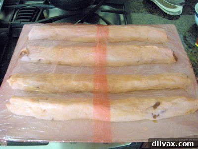 Rugelach dough meticulously spread with homemade prune lekvar and generously sprinkled with chopped nuts, ready for shaping.