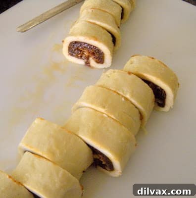 Beautifully shaped unbaked Rugelach rolls arranged on a baking sheet, prepared for refrigeration.