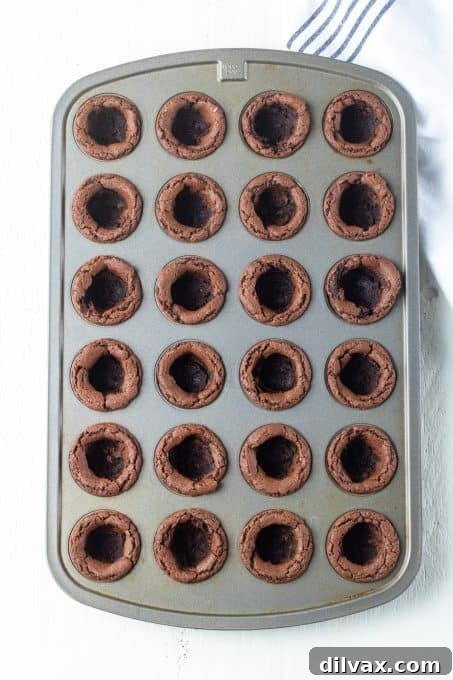 Close-up of perfectly formed chocolate cookie cups baked in a mini muffin tin, ready for filling.