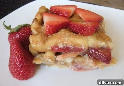 Side view of a baked strawberry waffle stack garnished with fresh strawberries.
