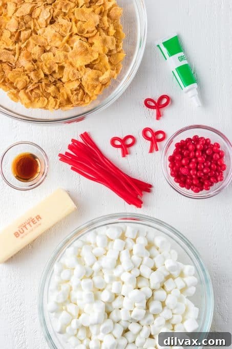 A collection of ingredients laid out, ready for making Cornflake Wreath Cookies: butter, marshmallows, vanilla, green food coloring, cornflakes, cinnamon candies, and licorice.