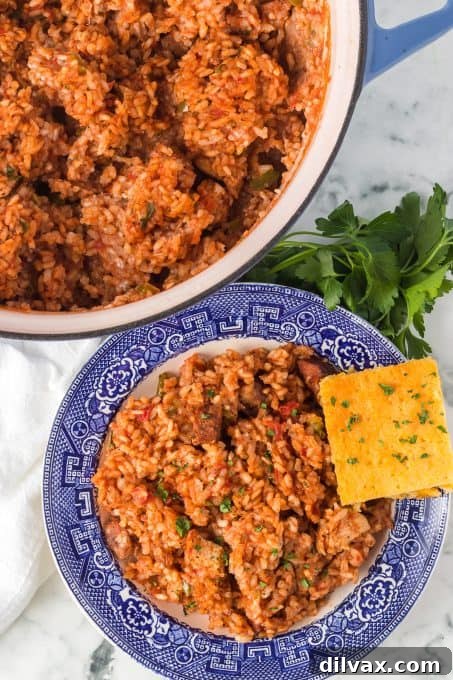 A vibrant and hearty Jambalaya with rice, Andouille sausage, tomatoes, and Cajun seasoning, ready to be served, with an optional shrimp addition, presented in a large white bowl.