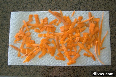 Thinly sliced carrots neatly arranged on a cutting board, ready for seasoning and baking.