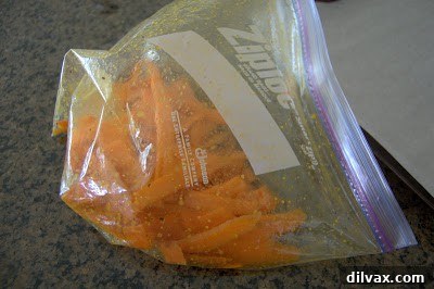 Sliced carrots being vigorously shaken in a Ziploc bag with olive oil and a blend of spices.
