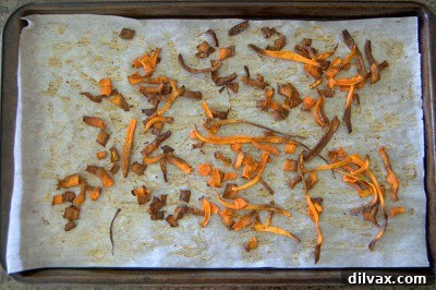 A fresh batch of crispy baked carrot chips, golden brown and perfectly textured, cooling on the baking sheet.
