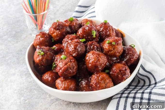 Sweet and Savory Cranberry Meatballs 2 Cranberry Meatballs, perfectly glazed in a rich, tangy sauce, ready to be served as an appetizer.