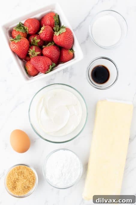 Ingredients laid out for making Strawberry Danish Hearts: cream cheese, sugar, vanilla, puff pastry, strawberries, egg, and sugars.