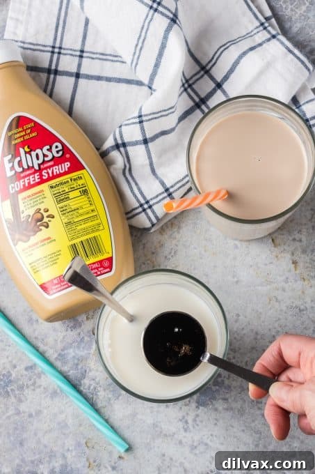 Milky Brew 6 Pouring Eclipse coffee syrup into a glass of milk.
