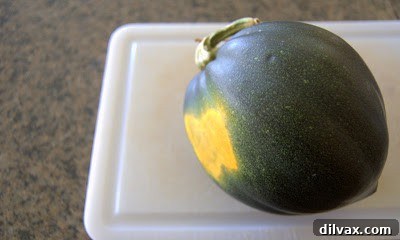 Two halves of raw acorn squash on a wooden cutting board, ready for preparation.