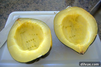 A fork piercing the tender flesh of a baked acorn squash half, indicating it's ready for scooping.