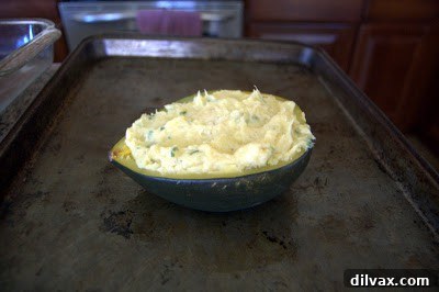 Acorn squash half filled with the creamy squash mixture, ready for the breadcrumb topping.