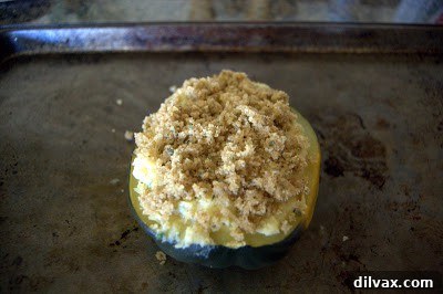 Buttered bread crumbs sprinkled over the filled acorn squash, preparing for the second bake.