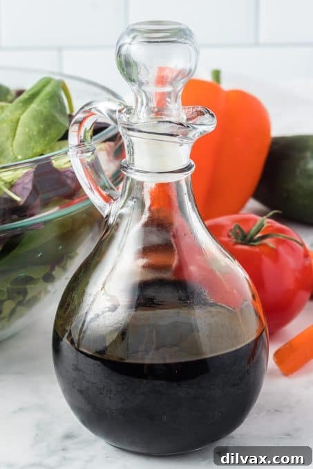 A small, stylish glass bottle containing a homemade balsamic glaze, showcasing its glossy, dark texture.