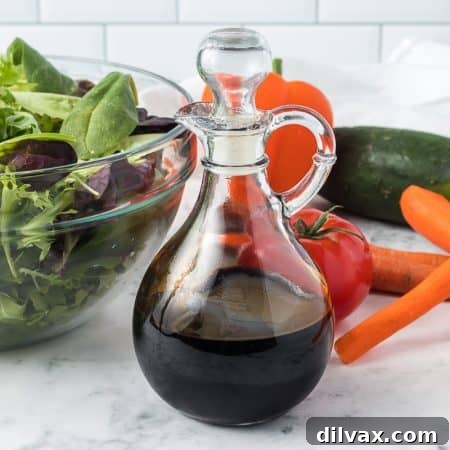 A clear glass cruet filled with a dark, glistening balsamic reduction, ready to be poured and enjoyed.