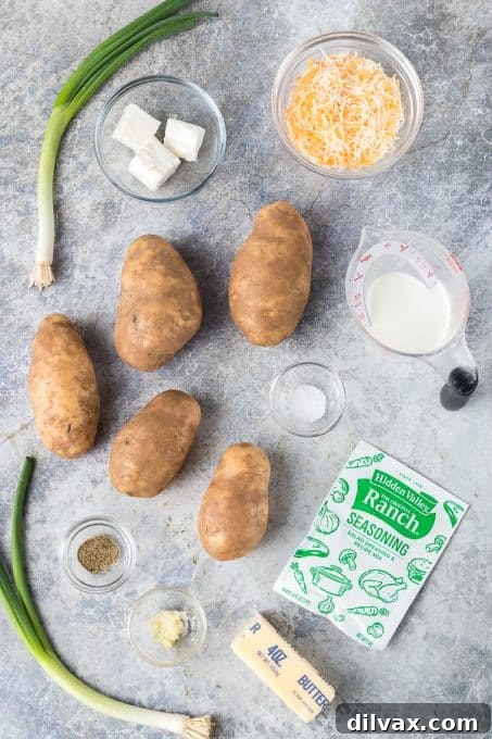Fresh ingredients laid out for making Ranch Mashed Potatoes: Russet potatoes, butter, ranch seasoning, cream cheese, Colby Jack cheese, milk, garlic, salt, pepper, and chives