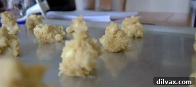 Cookie dough balls placed on a baking sheet, spaced for even baking.