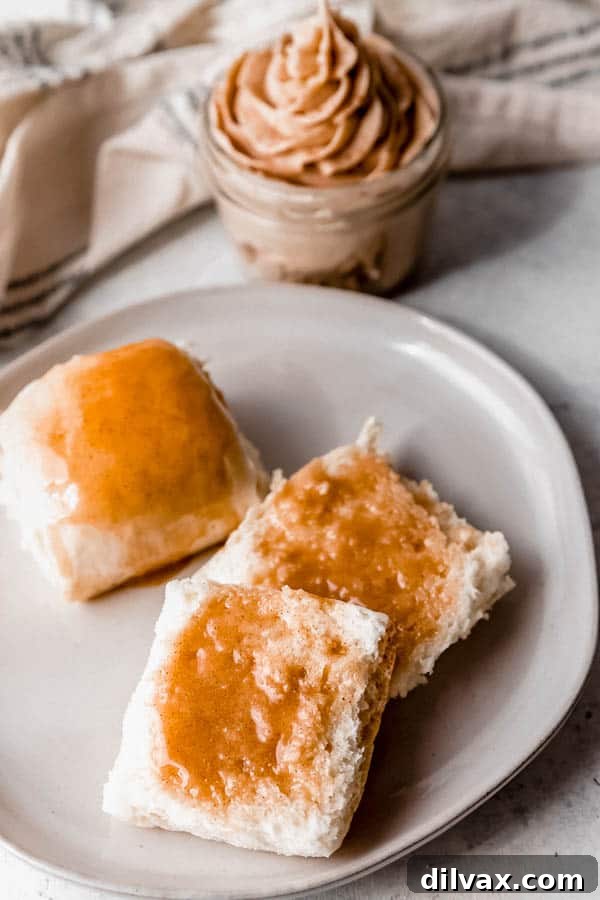 A warm Copycat Texas Roadhouse Roll served with a small bowl of creamy Cinnamon Honey Butter.