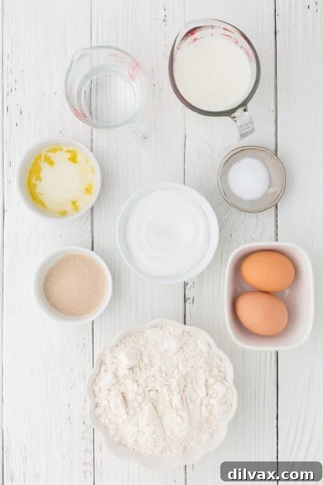 A flat lay image displaying all the essential ingredients for making Texas Roadhouse Rolls, including flour, milk, yeast, sugar, butter, and eggs.