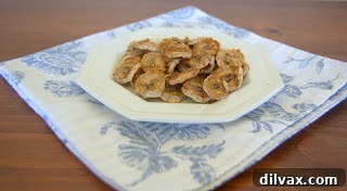 Deliciously golden baked banana chips on a baking sheet.