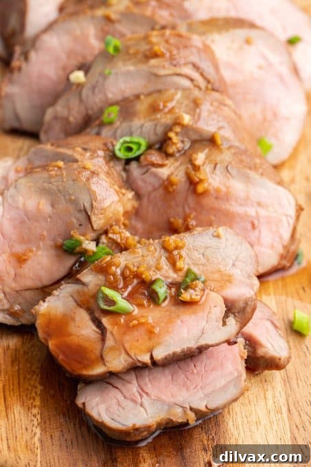 Sticky Asian Glazed Pork Tenderloin 3 Close-up of roasted pork tenderloin with Asian glaze and garnished with fresh herbs