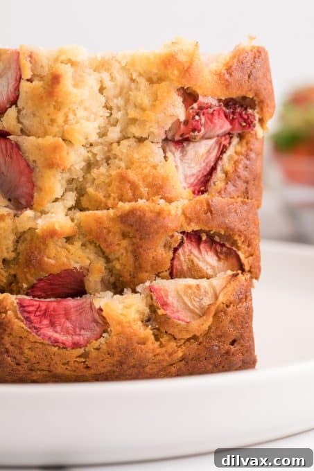 A close-up of a Strawberry Banana Bread loaf showing baked-in strawberries